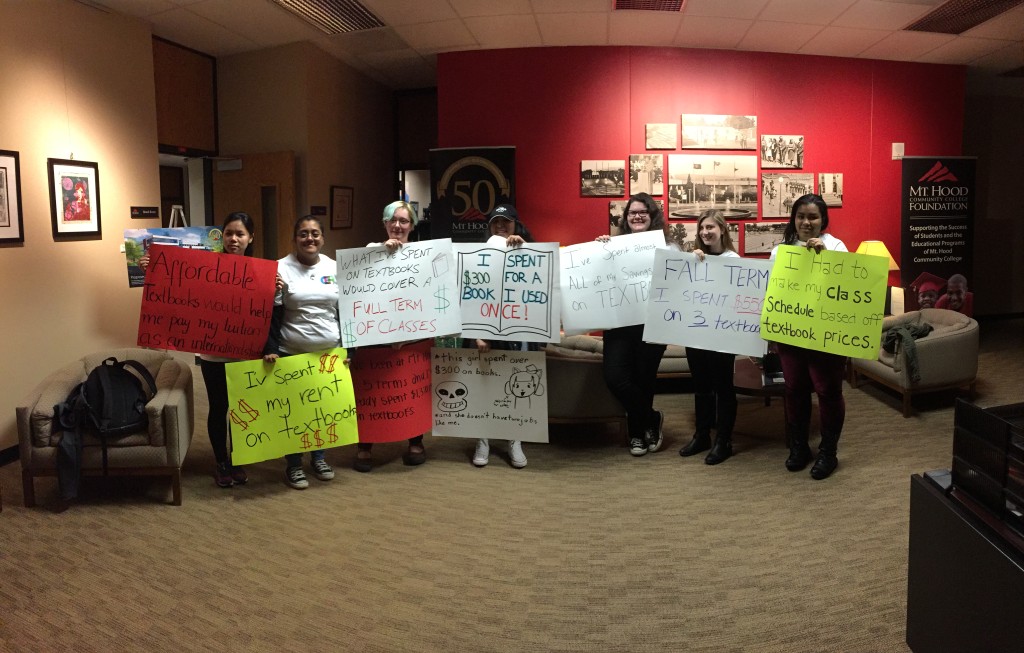 MHCC students hold up signs showing what high textbook prices mean to them. 
